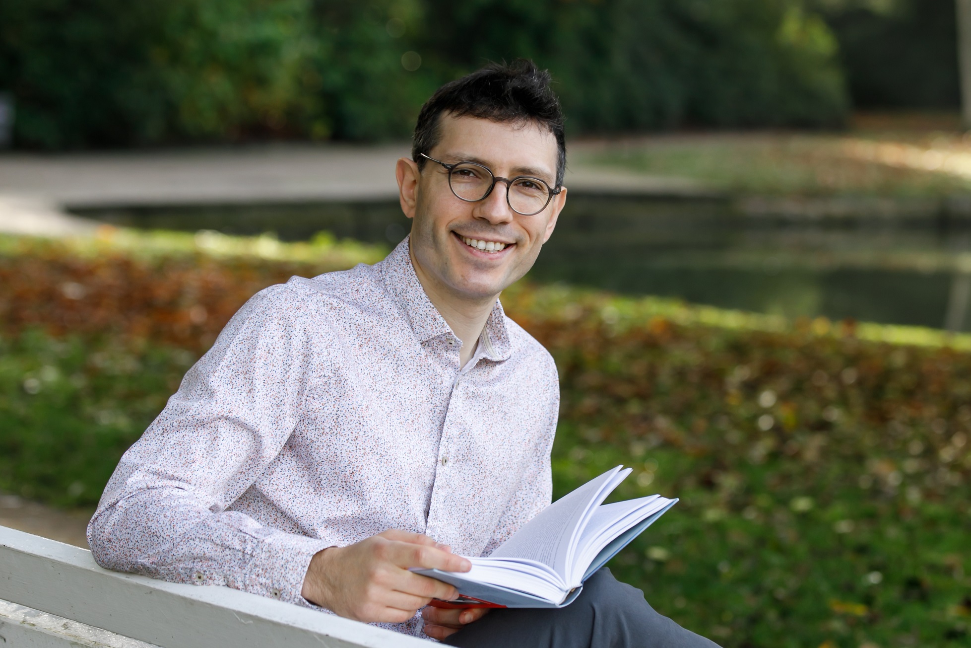 Germanist Evgenij Unker, lesend auf einer Bank im Lüneburger Kurpark.